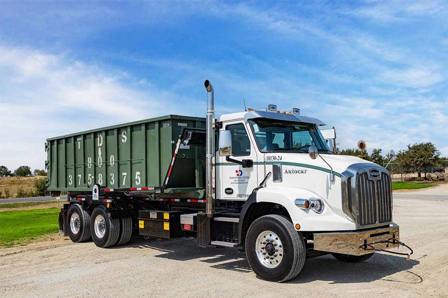 Green Roll off dumpster on TDS truck parked under blue sky